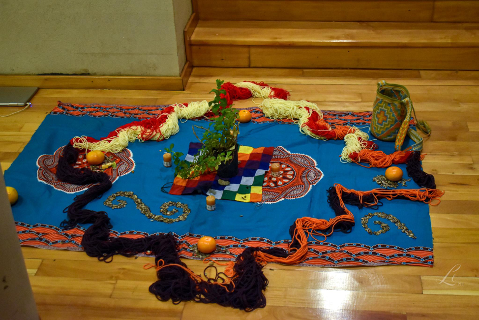 Chakana Espiritual, obra coletiva. Realizada sobre uma mola moçambicana. Com frutos, lãs, sementes, aromáticas, velas. 7 de dezembro de 2023.